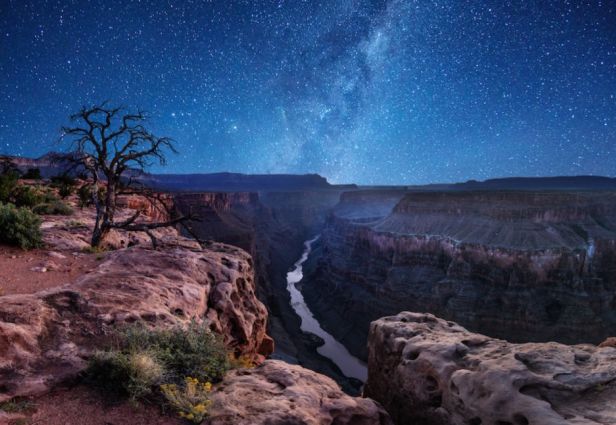 Snags, oor die Grand Canyon Nasionale Park, word die melkweg in die rivier weerspieël. Bron: Travel Awaits